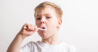 Tatlı çocuk ağzında bambu diş fırçasıyla poz veriyor, çocuk dişlerini fırçalıyor.