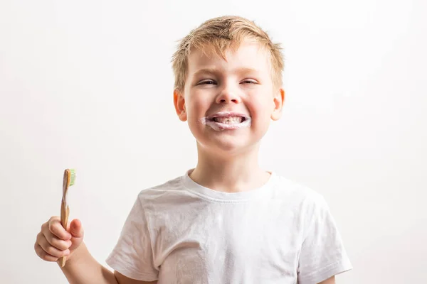 Cute boy posing with bamboo toothbrush in his mouth, child brushes his teeth — Stock Photo, Image