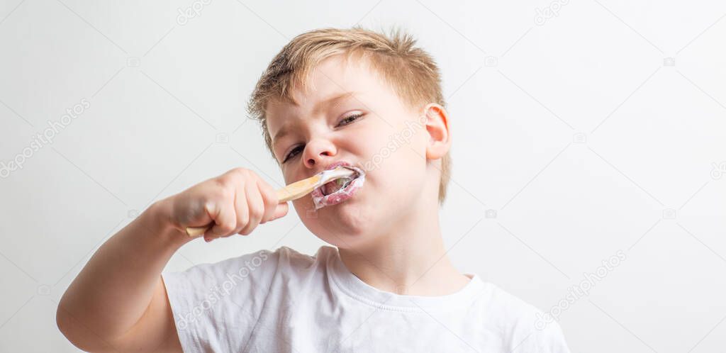 cute boy posing with bamboo toothbrush in his mouth, child brushes his teeth