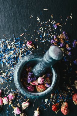 Siyah arkaplanda mermer bir havan topu içinde çiçekler