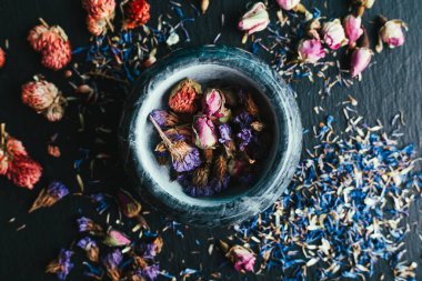 Siyah arkaplanda mermer bir havan topu içinde çiçekler