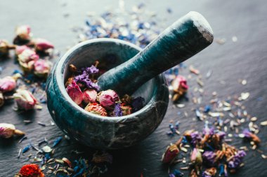 Şifalı bitkiler, Ayurveda, alternatif tıp, siyah arka planda mermer bir havan topunda kurutulmuş çiçekler.