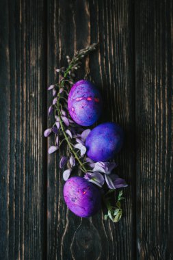 Koyu ahşap arka planda üç mor paskalya yumurtası.