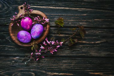 Yuvarlak tahta üzerinde leylak rengi paskalya yumurtaları