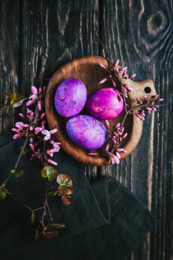 Yuvarlak tahta üzerinde leylak rengi paskalya yumurtaları