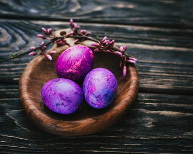 Yuvarlak tahta üzerinde leylak rengi paskalya yumurtaları