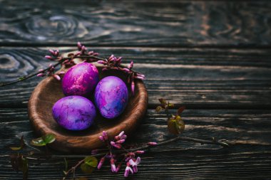 Yuvarlak tahta üzerinde leylak rengi paskalya yumurtaları