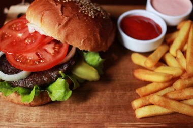 Hamburger ile domates, soğan, salata yaprakları, tuzlu salatalık ve