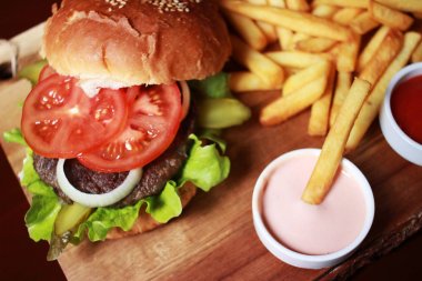 Hamburger ile domates, soğan, salata yaprakları, tuzlu salatalık 