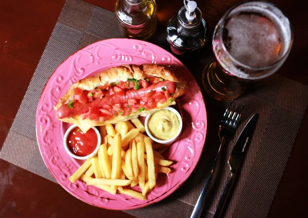 Perro caliente con salsa, cerveza fría y papas fritas — Foto de Stock