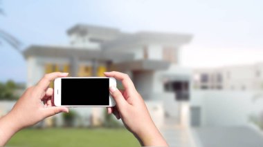 Beyaz mobil akıllı telefon üzerinde bulanık ev backgro tutan el
