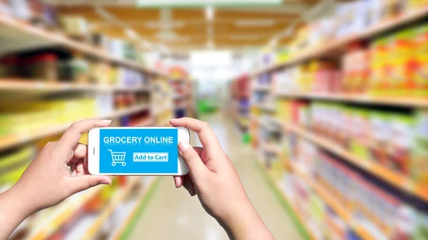 Ekranda online alışveriş bakkal ile akıllı telefon tutan el 