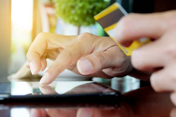 Elinde tablet ve kredi kartı olan adam içeride internetten alışveriş yapıyor.