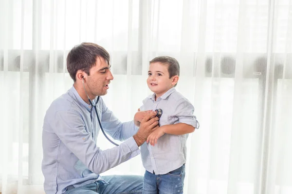 Father and Son playing doctors with boy holding a stethoscope an