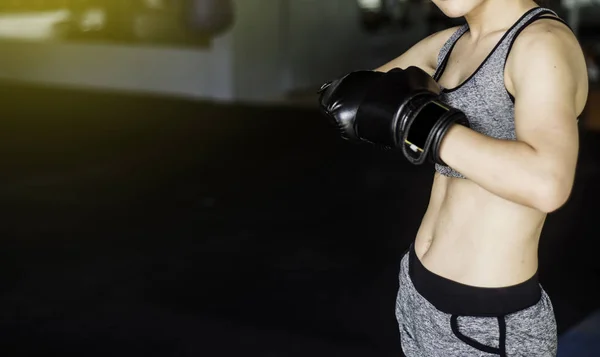 Young boxing woman with boxing gloves on black background