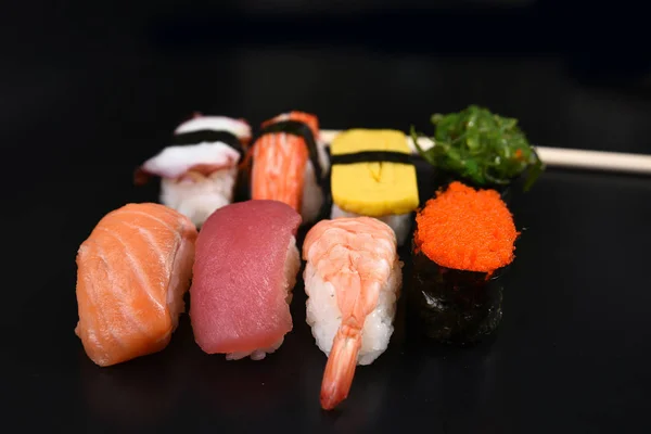 Sushi Thunfisch Nigiri in Essstäbchen über schwarzem Hintergrund — Stockfoto