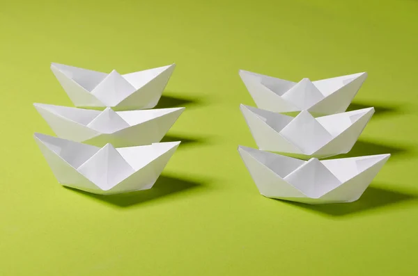 Concept photo for your project. White origami on green background. Group of handmade ship.