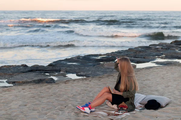 Bella giovane donna seduta sulla spiaggia, guardando le onde — Foto Stock