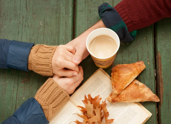 Loving couple holding hot coffee in hands on wooden background