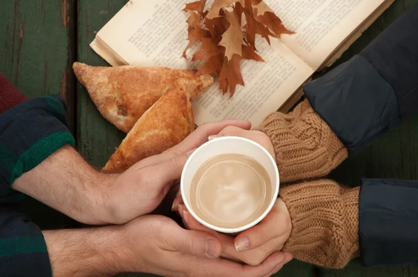 Любящая пара держит горячий кофе в руках на осеннем фоне — стоковое фото
