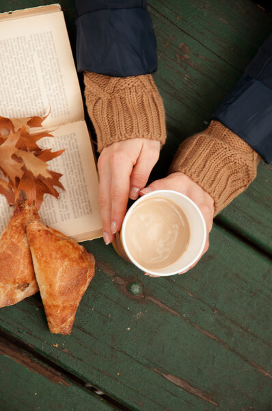 Woman holding hot coffee in hands on autumn background Stock Picture