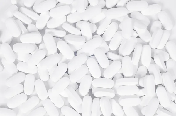 Pílulas brancas no fundo branco. — Fotografia de Stock