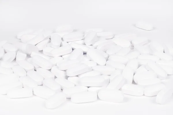 Pílulas brancas no fundo branco. — Fotografia de Stock