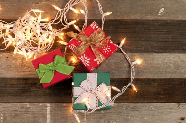 Geschenke und Weihnachtsbeleuchtung auf Holztisch — Stockfoto