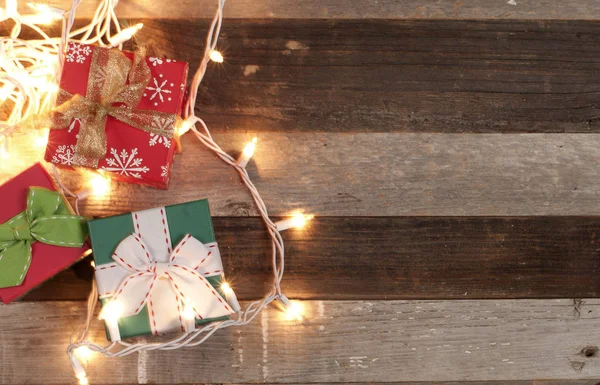 Geschenke und Weihnachtsbeleuchtung auf Holztisch — Stockfoto
