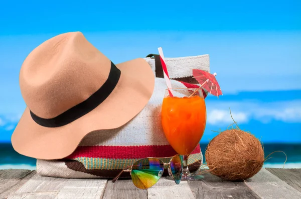 Refrescante cóctel naranja en la mesa de playa. Sombrero y bolso de verano — Foto de Stock