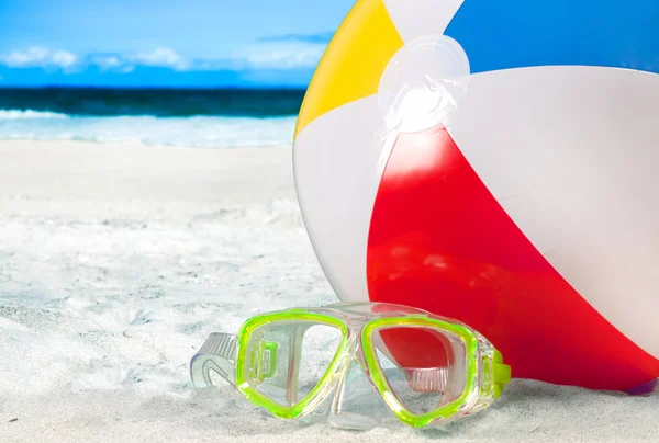 Mask goggles and color ball on a sand on beach background