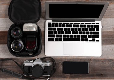 Dizüstü bilgisayar, akıllı telefon, fotoğraf makinesi ve ahşap arka plan üzerinde kulaklık