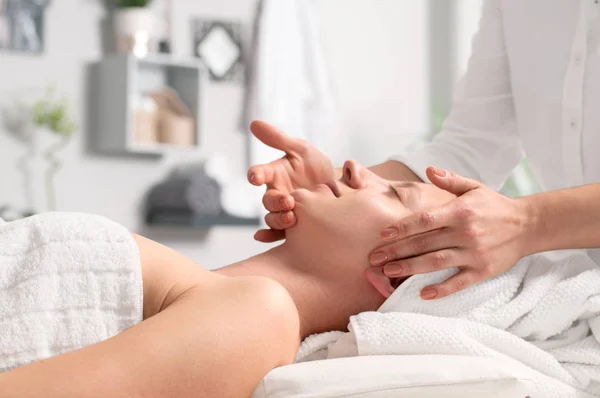 Masajista haciendo masaje facial de mujer en salón de spa — Foto de Stock