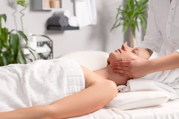 Masajista haciendo masaje facial de mujer en salón de spa — Foto de Stock