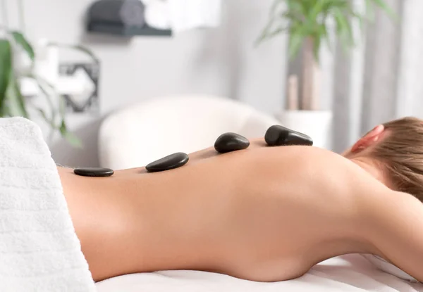 Mujer recibiendo masaje de piedra caliente en el salón de spa . — Foto de Stock