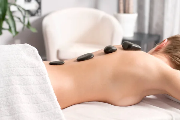 Kvinna att få massage med varma stenar i spasalong. — Stockfoto