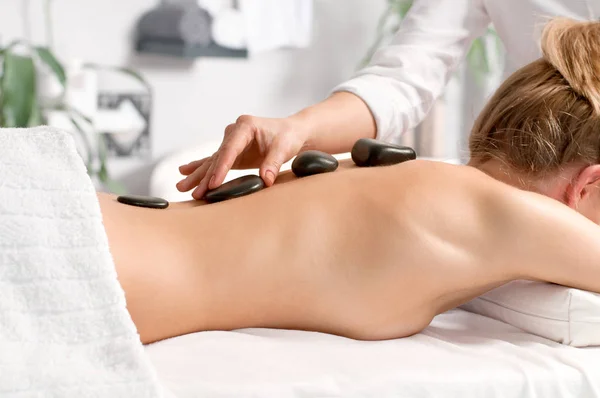 Mujer recibiendo masaje de piedra caliente en el salón de spa . — Foto de Stock