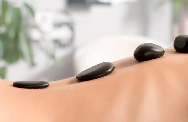 Woman getting hot stone massage in spa salon. Royalty Free Stock Images