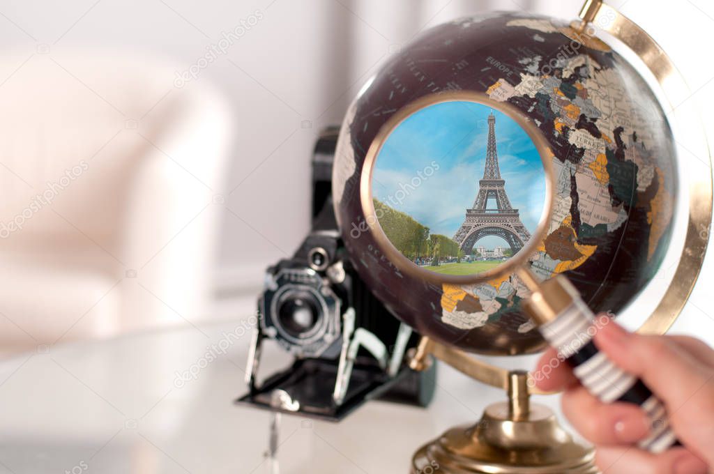 Eiffel Tower on globe through magnifying glass