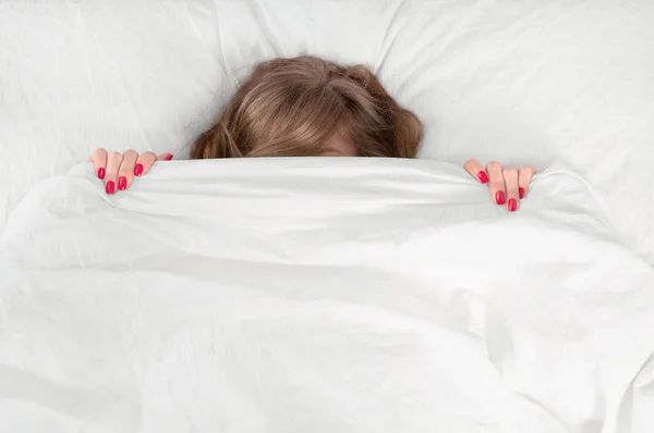 Potret wanita muda yang cantik berbaring di tempat tidur di bawah selimut — Stok Foto