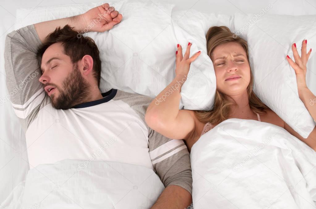 Couple sleeping in bed.  Woman can't sleep because of her man's snoring