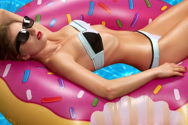 Frau im Bikini auf der aufblasbaren Matratze im Schwimmbad. — Stockfoto
