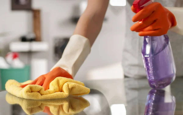 Vrouw in handschoenen tabel met spray reiniging. — Stockfoto