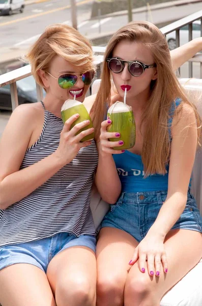 Дві молоді жінки розважаються і п'ють коктейль в літній день — стокове фото