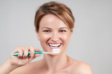 Mutlu genç bir kadın dişlerini fırçalıyor..