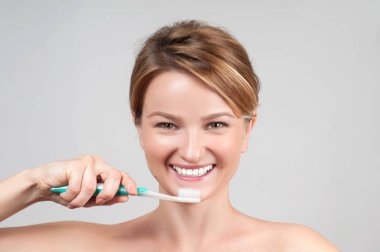 Mutlu genç bir kadın dişlerini fırçalıyor..