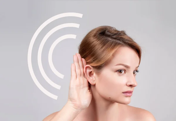 Mujer cogida de la mano cerca de su oído y escuchando cuidadosamente — Foto de Stock