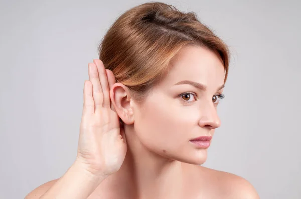 Mujer cogida de la mano cerca de su oído y escuchando cuidadosamente — Foto de Stock