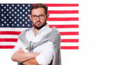 Amerika Birleşik Devletleri bayrağı arka plan üzerinde gülümseyen genç adam. 