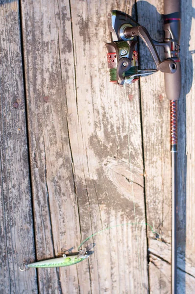 Aparejos de pesca: spinning de pesca, anzuelos y señuelos en el muelle de madera —  Fotos de Stock